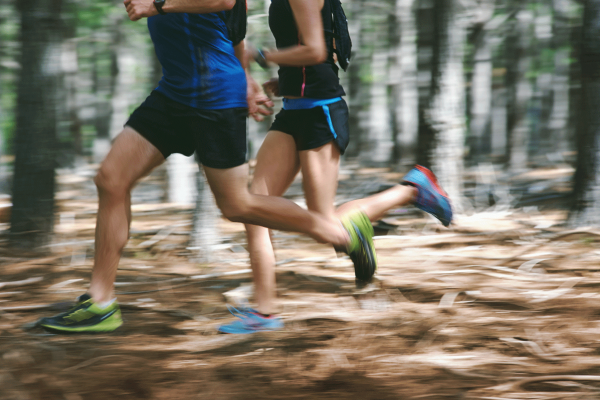 Zwei Läufer in Sportkleidung laufen durch den Wald